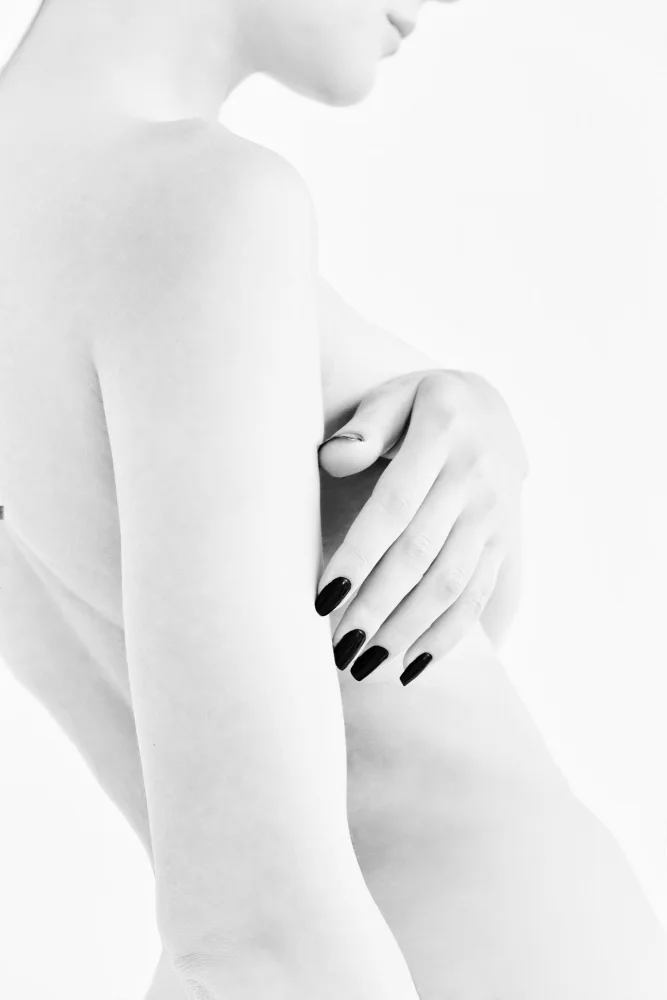 Alexandr: body parts of a naked girl torso and hand pressing her breasts with a black manicure on her nails