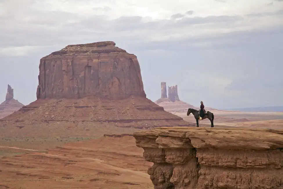 Unknown: Donna navajo a cavallo nella Monument Valley