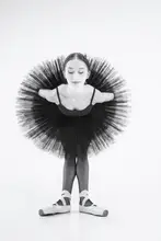 Alexandr: peacock. a ballerina in a black tutu is leaning forward with her arms crossed behind her back